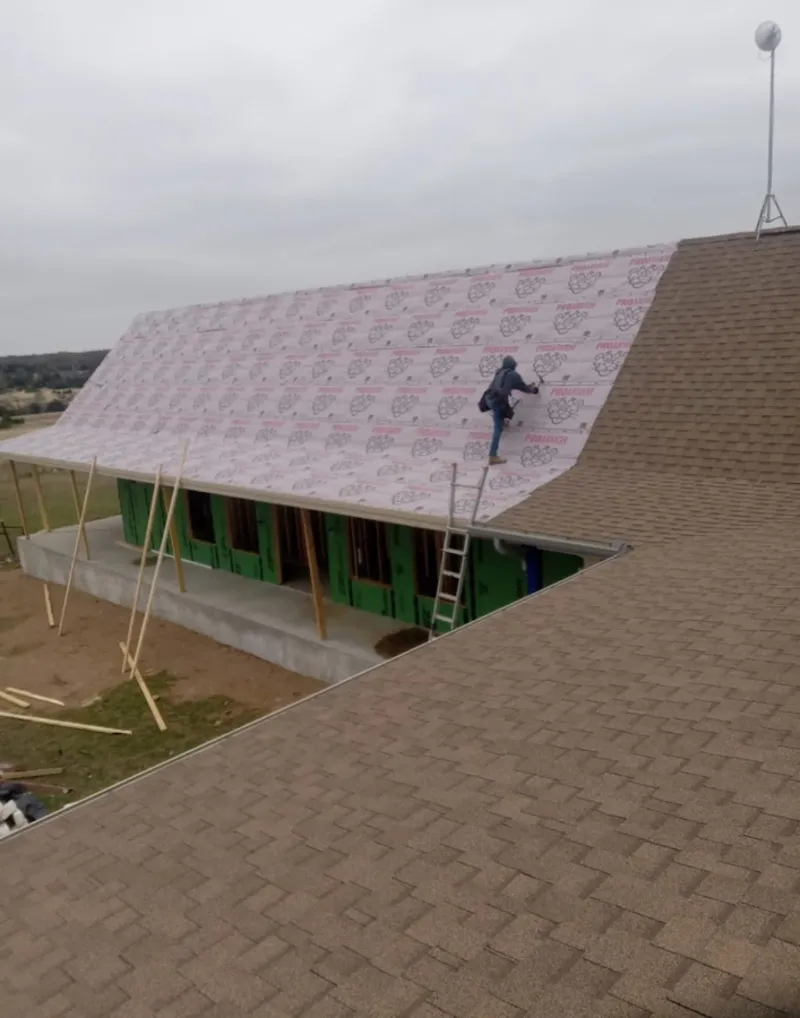 Worker preparing underlayment for a metal roof installation in Palmyra